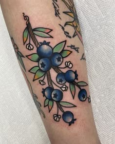 a tattoo with blueberries and leaves on it