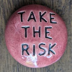 a pink button with the words take the risk written in black ink on top of it