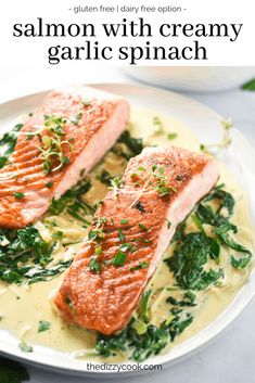 salmon with creamy garlic spinach sauce on a white plate and green garnish