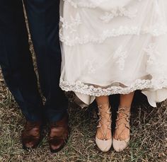 two people standing next to each other in front of grass and dirt with their feet on the ground