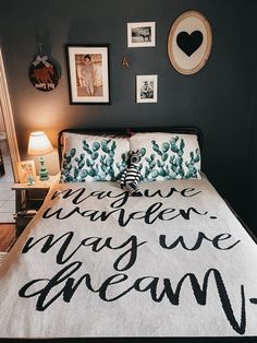 a bed with a white comforter and black writing on the cover in a bedroom