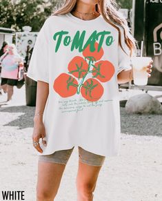 Embrace retro vibes with this vintage-inspired tee featuring a bold, oversized tomato graphic. Perfect for those who love a pop of color and a touch of nostalgia, this shirt adds a playful twist to any casual outfit. The text at the bottom says, "You say tomato we say pomodoro, let's call the whole thing off and explore the delicious ways to eat the juicy sun ripened fruit" We use professional quality DGT printing on all our apparel. Direct-to-garment, or DTG, is a high quality printing method t Cotton T-shirt For Gardening In Summer, Green T-shirt For Gardening In Summer, White Letter Print T-shirt For Gardening, Casual T-shirt For Gardening In Spring, Casual Spring T-shirt For Gardening, Cottagecore Vintage Aesthetic, Tomato Graphic, Tomato Girl Summer, Vintage Aesthetic Retro