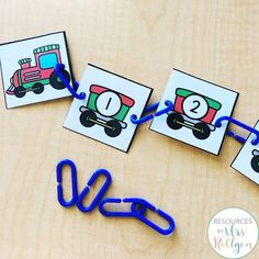 some blue paper clips sitting on top of a wooden table next to pictures and scissors