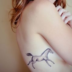 a woman with a horse tattoo on her left shoulder and right arm behind her back