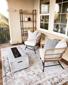 two wicker chairs sitting on top of a rug in front of a window next to a fire place