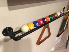 pool balls are lined up on a rack in front of a wall mounted billiard's cue