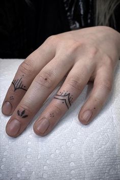 a woman's hand with two small tattoos on her fingers and the other finger