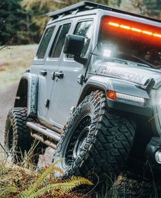 a jeep is parked in the woods with its lights on