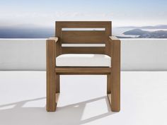 a wooden chair sitting on top of a white floor next to a wall and ocean