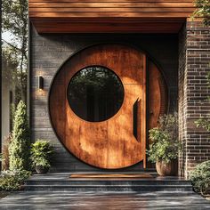 a wooden door with a circular window on the side of a brick building next to potted plants