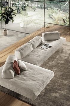 a large white couch sitting on top of a wooden floor next to a plant in a living room