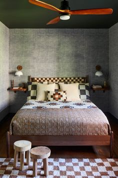 a bed sitting in a bedroom next to a table with two stools on it