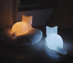 a cat shaped pillow sitting on top of a table next to a lit up light