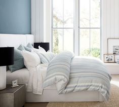 a bedroom with blue walls and white bedding