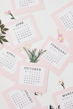 calendars with flowers and plants on them sitting on top of a white tablecloth