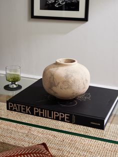 a vase sitting on top of a book next to a glass table