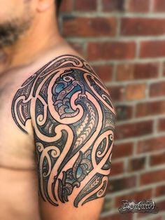 a man's arm with an intricate tattoo design on his left shoulder and chest