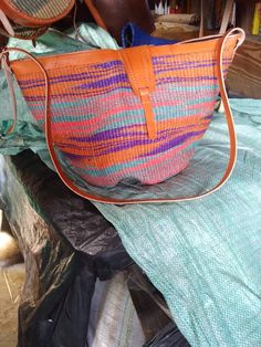 an orange and blue bag sitting on top of a bed next to a purse with handles