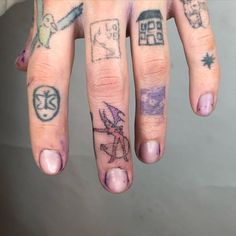 a person's hand with tattoos on it and two fingers that have different designs