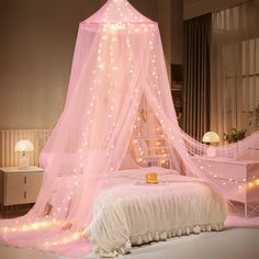 a bed with a pink canopy and lights on the top, next to a night stand