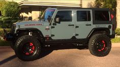 a gray and red jeep parked in front of a building