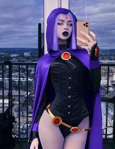 a woman dressed in purple and black is taking a selfie with her cell phone