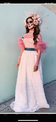 a woman in a pink dress standing next to a wall wearing sunglasses and a headdress