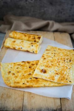 three flat breads sitting on top of a wooden cutting board