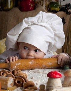 a baby wearing a chef's hat and holding a rolling pin