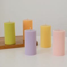 four different colored candles sitting next to each other on a white counter top in front of a mirror