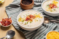 three bowls filled with soup on top of a table next to spoons and other food