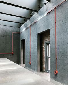 an empty room with concrete walls and red piping