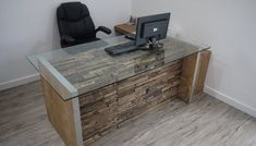 an office desk with a computer on it and a chair in the corner next to it