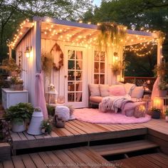 an outdoor living area is lit up with fairy lights and pink rugs on the deck