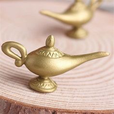 two small brass teapots sitting on top of a wooden table next to each other