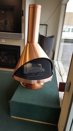 a copper colored stove top oven sitting on green carpeted floor next to a fireplace