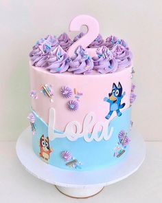 a two tiered cake with purple frosting and decorations on the top is decorated with cartoon characters