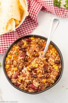 a bowl filled with chili and rice next to tortilla chips on the side