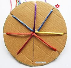 an ornament made out of cardboard with yarn and scissors on it's side