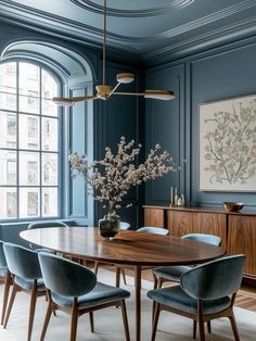 an elegant dining room with blue walls and wooden table surrounded by blue upholstered chairs