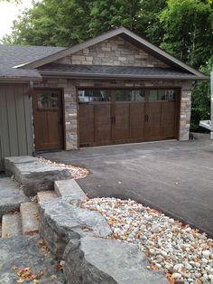 a house with two garages and stone steps leading up to the front door area