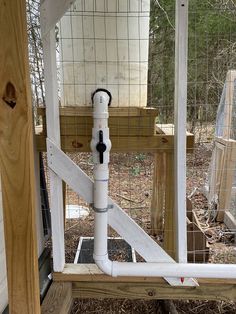 a white pipe attached to the side of a chicken coop