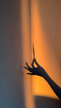 a person's hand reaching up towards the light coming from behind their shadow on a wall