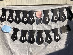 a happy birthday banner with ties hanging from it's sides and an image of a baby in the middle