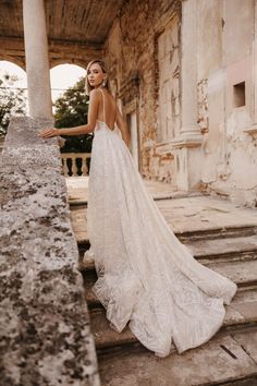 a woman in a white wedding dress standing on some steps with her back to the camera