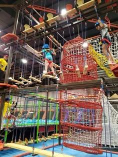 children are playing in an indoor trampoline course with ropes and ladders hanging from the ceiling