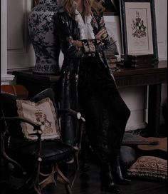 a woman sitting on a chair in front of a table with vases and pictures