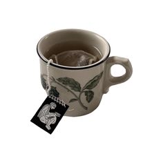 a white cup filled with tea next to a tag