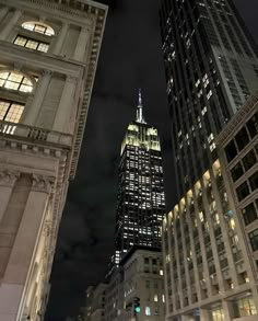 the empire building is lit up at night in new york city, ny on an overcast day