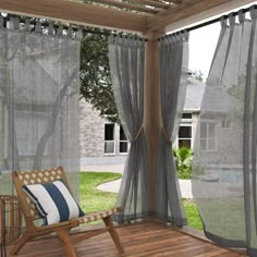 a chair sitting on top of a wooden deck next to a window covered in sheer curtains